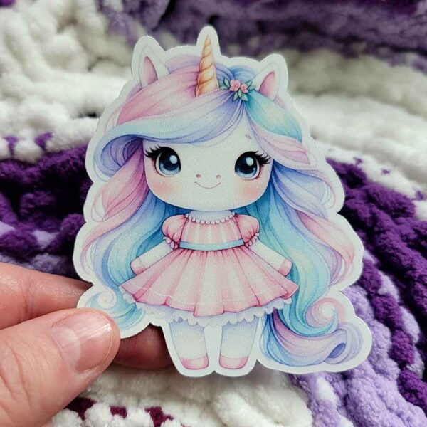 Cute vinyl sticker of a pastel-colored unicorn princess with a golden horn, large blue eyes, and a pink dress, exuding a whimsical, magical charm.