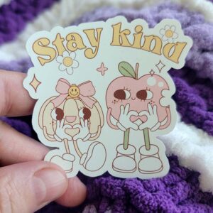 Cute vinyl sticker featuring Pippa the Pumpkin and Appleton the Apple with a "Stay Kind" message, surrounded by flowers and sparkles.