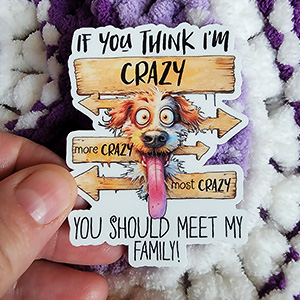 A humorous vinyl sticker featuring a zany dog with wide eyes and a tongue sticking out, surrounded by wooden signs with the text "If you think I'm crazy, you should meet my family!"