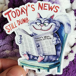 A mischievous, smiling cat named Snarky Paws reads a newspaper with the headline "Humans Still Dumb," while sitting on a green chair.