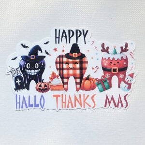 A vinyl sticker with three teeth dressed for Halloween, Thanksgiving, and Christmas, labeled "Happy HalloThanksMas."