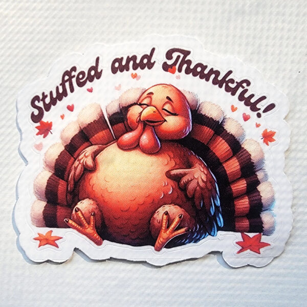 Sticker of a happy, plump cartoon turkey with "Stuffed and Thankful!" written above and decorated with hearts and autumn leaves.